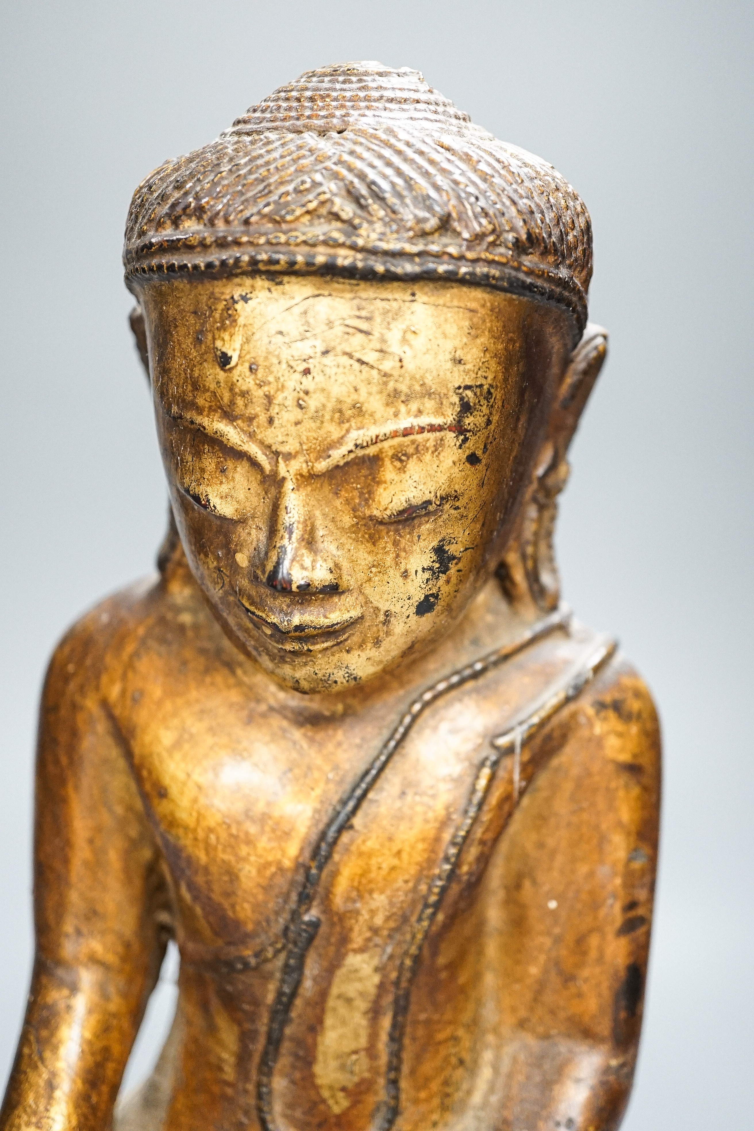 A Burmese gilded carved wooden figure of Buddha, 35 cms high.